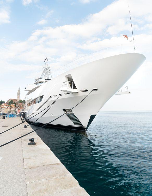 A spotless, high-gloss luxury white yacht moored peacefully in a calm harbor
