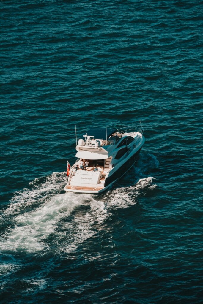 An elegant motor yacht cruising smoothly through clear, turquoise coastal waters, leaving a clean wake behind its hull