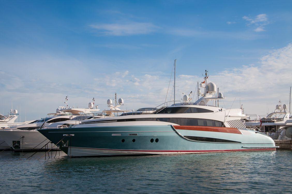 A luxury motor yacht anchoring in calm, open coastal waters under a bright sun